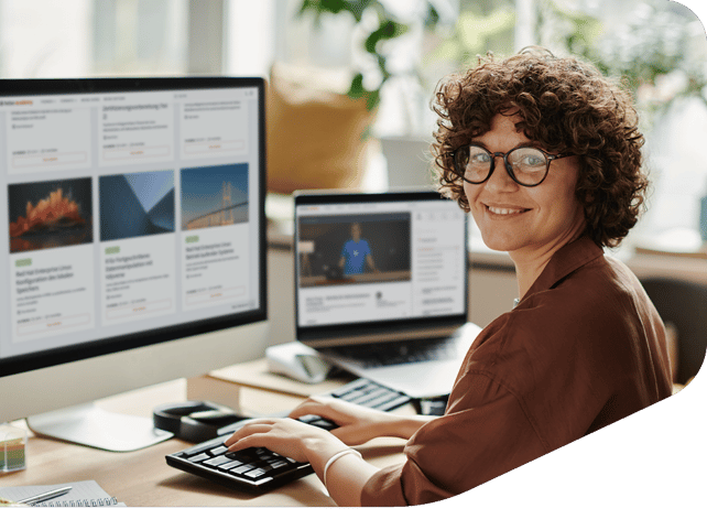 Person mit lockigen Haaren und Brille arbeitet an Dual-Monitor-Setup mit Bildergalerie und Videocontent.